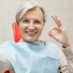 Patientin mit perfektem Lächeln, die ein Selfie macht und bloggt, bei einer zahnärztlichen Untersuchung.