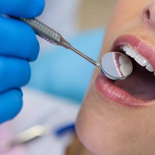 Dentist holding angled mirror by woman at medical clinic